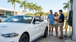 A modern white car rental driving along a sunny, palm-lined road in Miami, Florida