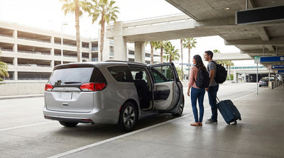 The modern Miami Airport car rental center with palm trees in front under a sunny, clear blue sky