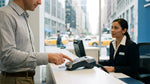 Customer entering a PIN on a credit card terminal at a New York car hire desk