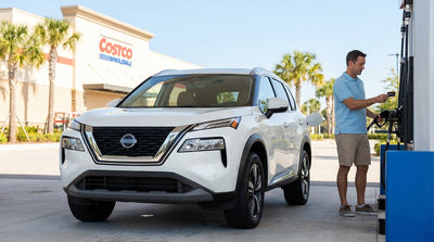 A driver refueling a silver car hire at a Costco gas station pump on a sunny day in Florida
