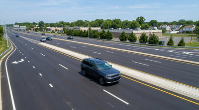 A driver in their car hire navigates a multi-lane highway with complex turn signs near New York
