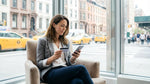 A person holding a credit card and keys for their car hire with a New York City street in the background