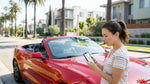 Person looking at a smartphone inside a car hire parked on a Los Angeles street
