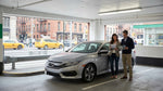 A car rental driving across the Brooklyn Bridge with the iconic New York City skyline in the background