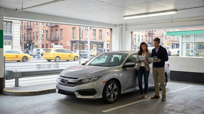 A car rental driving across the Brooklyn Bridge with the iconic New York City skyline in the background