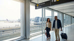 The SFO AirTrain arriving at the glass-walled car rental center in San Francisco under a bright, clear sky