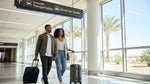 Traveler with luggage at a Las Vegas airport baggage claim looking up at a car rental directional sign