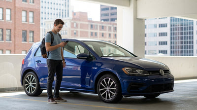 Young driver beside a modern car rental on a bustling New York City street with yellow cabs in the background