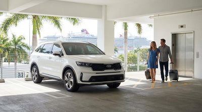 A white convertible car hire drives towards PortMiami with a large cruise ship and the city skyline in the background