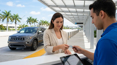 A smiling woman returns the keys for her United Estates car hire at a rental counter