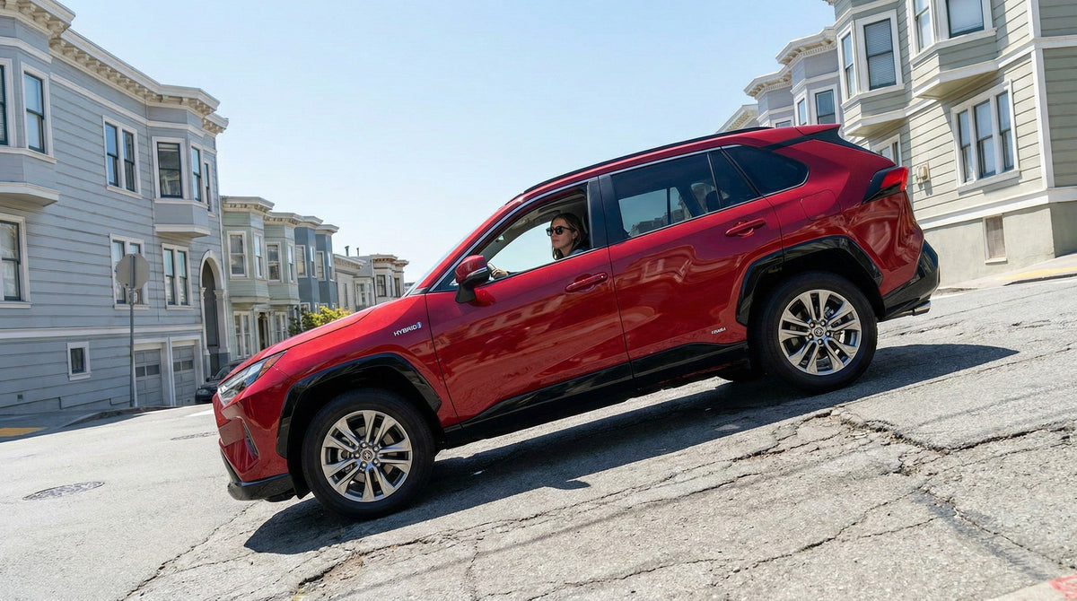 A red rental car driving up a steep hill lined with Victorian homes in San Francisco.