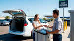 Woman handing the keys of a white minivan to an attendant at the car rental return drop-off.