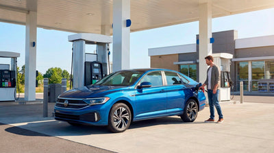 Traveler refueling a fuel-efficient blue sedan car hire at a gas station to save on travel costs.