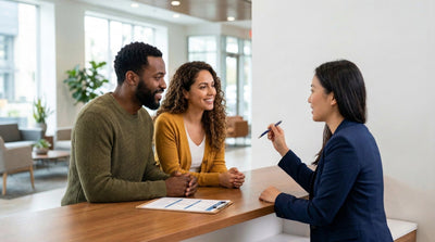 Happy couple compares weekly vs daily rate options at a clean car rental counter.