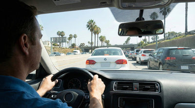 Driver in a white Volkswagen Jetta car rental navigating Los Angeles traffic near LAX airport.