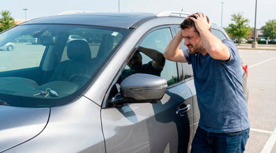Frustrated man realizing he has locked his keys inside his grey SUV rental car.