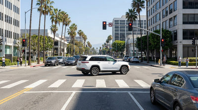 A car hire stops before the white lines of a busy intersection in downtown Los Angeles