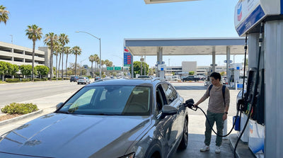 A person refueling their car hire at a gas station pump on a sunny day in Los Angeles