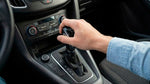 Close up of a driver shifting gears in a manual car rental, illustrating stick shift availability in the US.