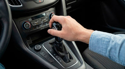 Close up of a driver shifting gears in a manual car rental, illustrating stick shift availability in the US.