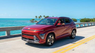A red Hyundai Kona driving across a long bridge over turquoise water on a sunny day heading towards Key West.