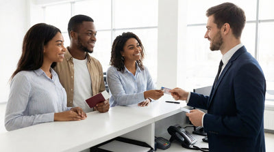 A group of three friends at a car hire desk, presenting a driving licence and a passport as a second form of ID to an agent.