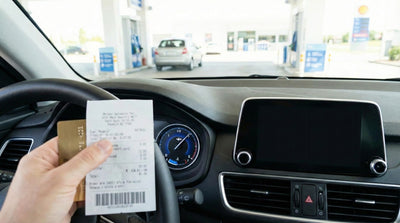 Driver holding a gas receipt near the dashboard fuel gauge during a New York car hire return.