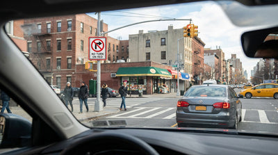 A car hire stopped at a red light at a busy New York City intersection with a no turn on red sign visible