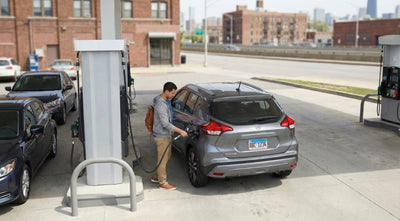 A driver refueling a modern car hire at a gas station with the New York skyline in the distance