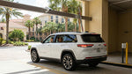 A white Jeep Grand Cherokee L with Florida license plates drives out of a covered parking garage exit.