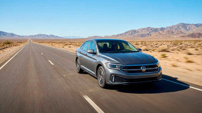 Grey Volkswagen sedan rental car driving on a long, open desert highway road trip.