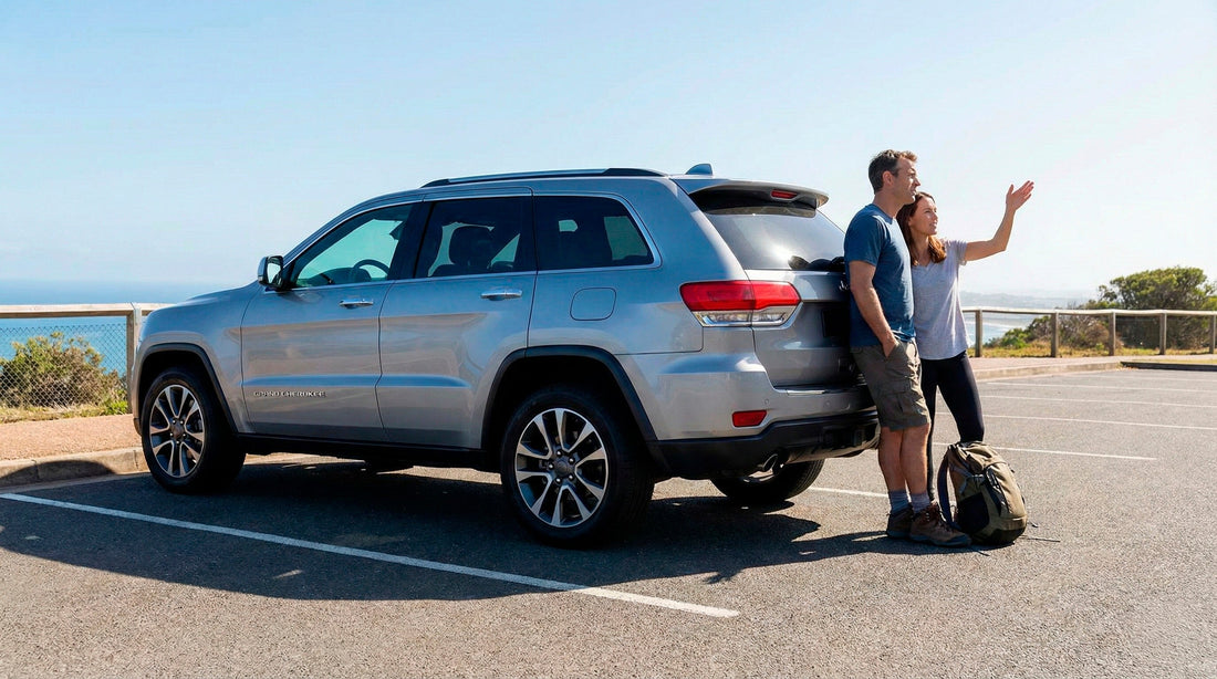 Couple stopping to sightsee near the coast with their silver Jeep Grand Cherokee rental car.