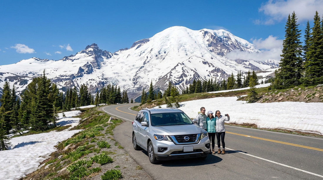 Family standing near a silver Nissan Pathfinder car rental with Mount Rainier snowy peaks in the background.