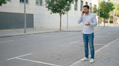 Worried man talking on the phone in a parking lot after his rental car was stolen.