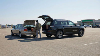 A customer discusses switching rental cars with an agent in a parking lot, pointing between a blue SUV and a white sedan.