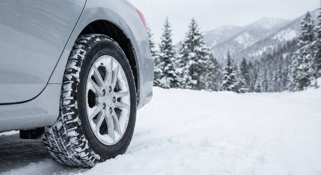 A close-up detail shot of a rental car's wheel and tire resting on a snowy surface, highlighting the tire tread in winter conditions.